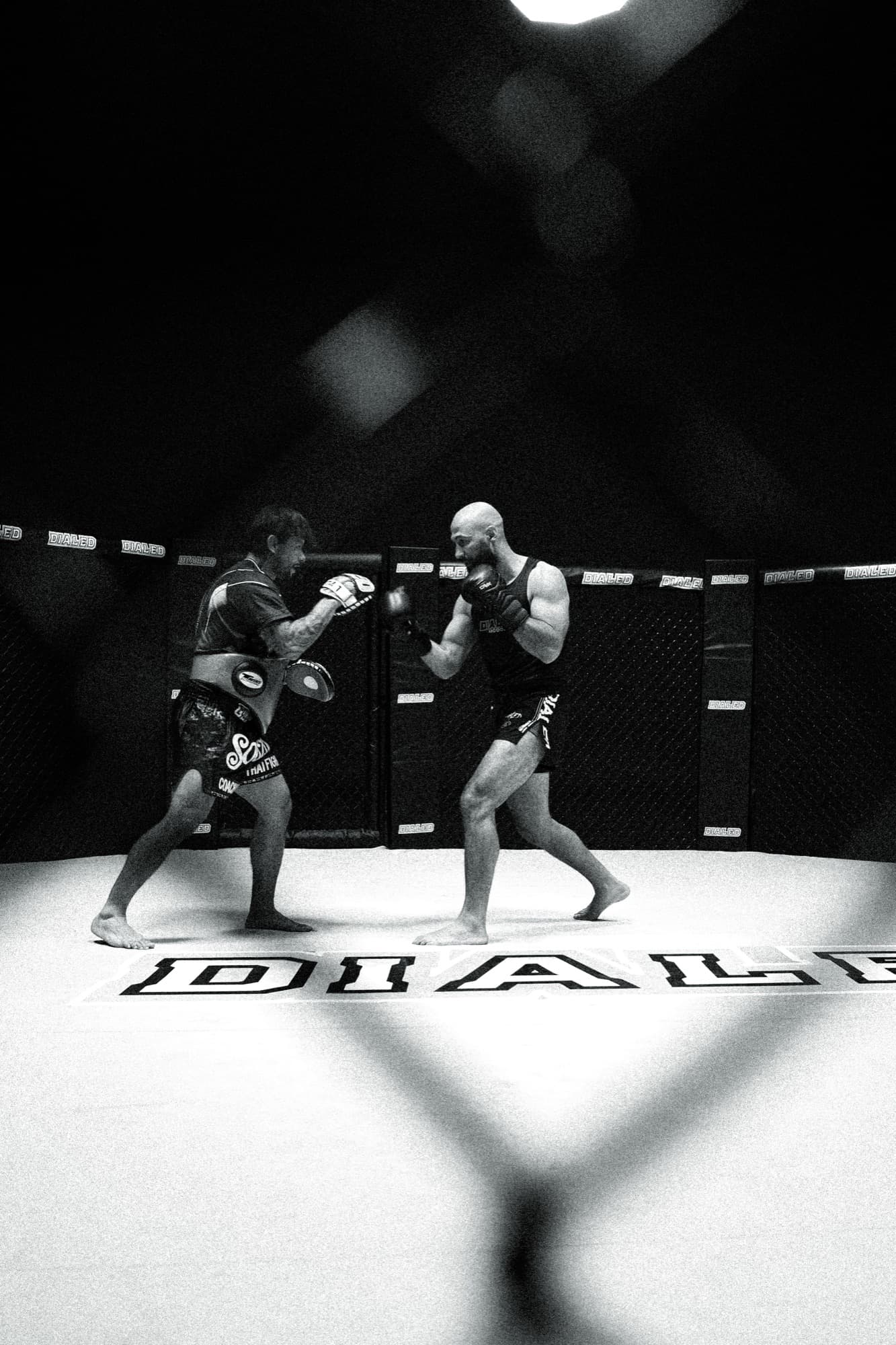 Coach holding pads for a fighter inside the cage